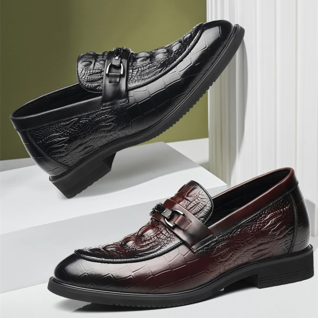Black and brown leather loafers with crocodile texture on a white surface.