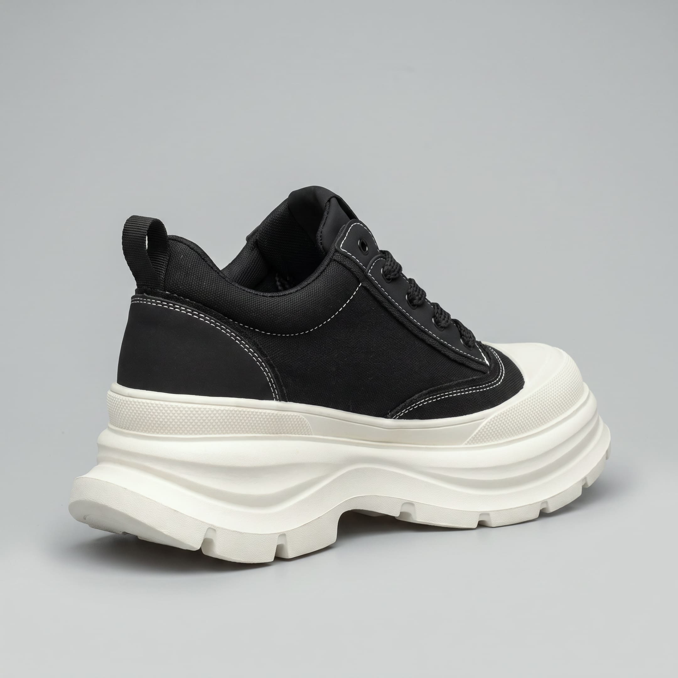 FORCIANO ATLAS Black elevator sneaker with a White chunky sole, shown from a rear three-quarter angle with the canvas and leather upper visible.