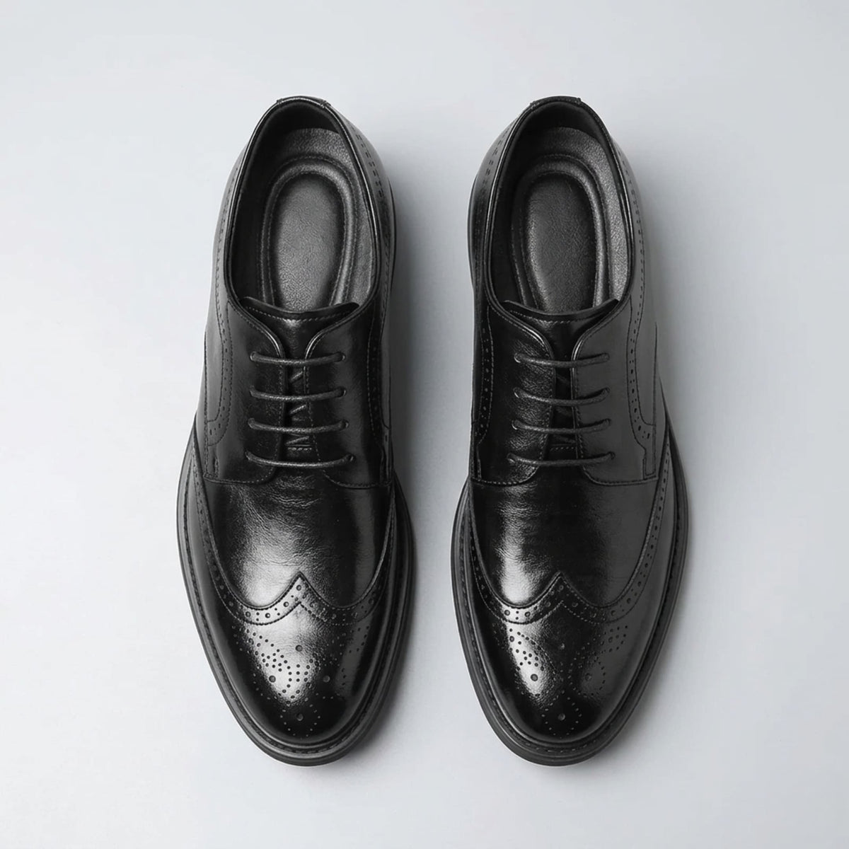 Top view of a pair of FORCIANO FAIRMONT black height increasing dress shoes showing laces, openings and brogue toe detailing.