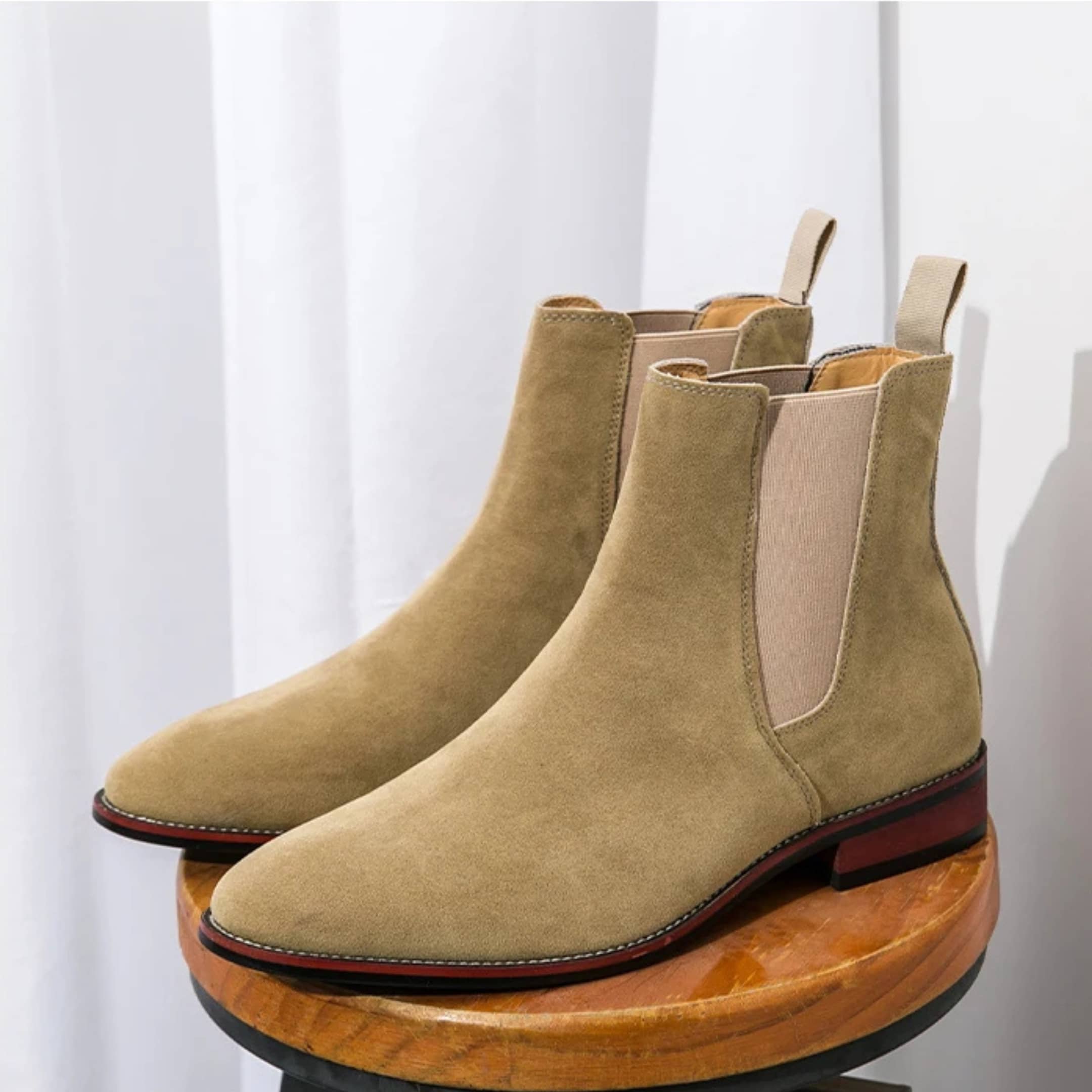 FORCIANO IVORY beige suede elevator Chelsea boots displayed as a pair on a wooden stool.