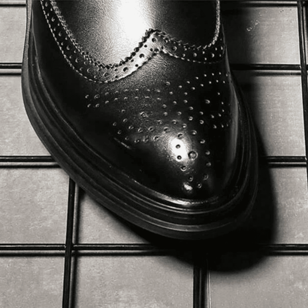 Close-up of the FORCIANO ALTIER black leather elevator boot toe showing polished finish, brogue perforations and layered sole edge.