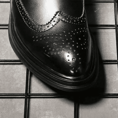 Close-up of the FORCIANO ALTIER black leather elevator boot toe showing polished finish, brogue perforations and layered sole edge.