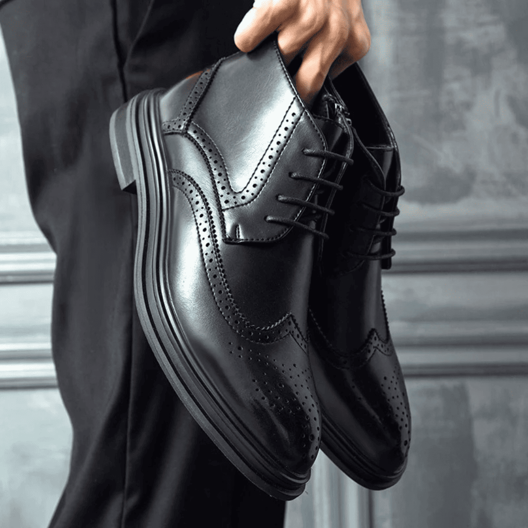 FORCIANO ALTIER black leather elevator boots held as a pair, showing the lace-up design, perforated detailing and raised boot profile.