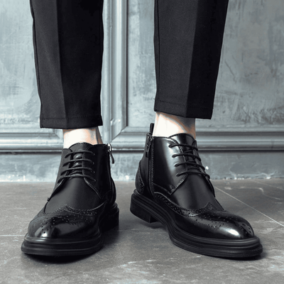 FORCIANO ALTIER black leather elevator boots worn with black trousers in a front lifestyle view, showing lace-up fronts and brogue toe detailing.