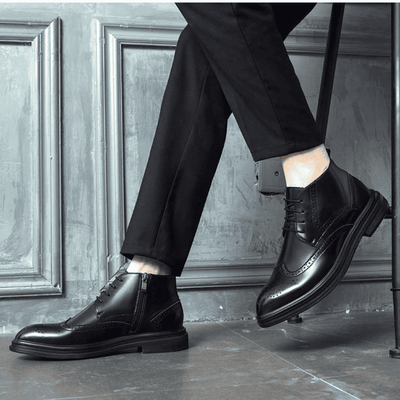 FORCIANO ALTIER black leather elevator boots shown worn in a seated lifestyle pose, displaying side and front angles with brogue accents.