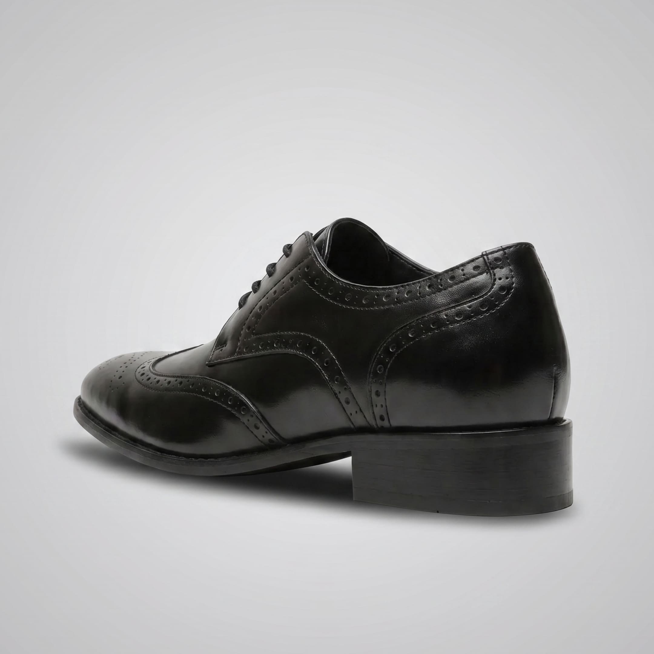 FORCIANO BROGUE black premium leather elevator dress shoe in rear three-quarter view, showing the heel and decorative brogue perforations.