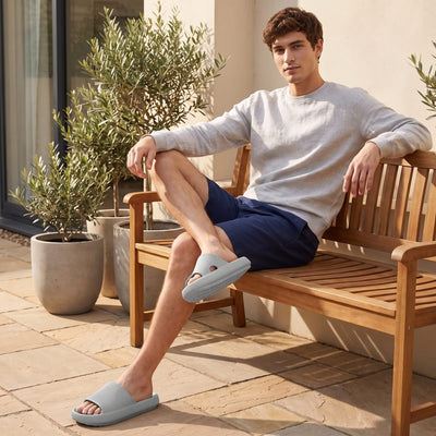 DUNE height increasing shoes in light grey worn with navy shorts while sitting on a wooden bench outdoors.