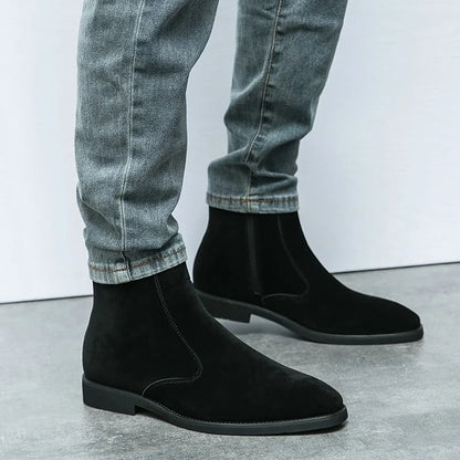 FORCIANO ECLIPSE black suede Chelsea boots shown on foot with gray jeans in a standing lifestyle view.