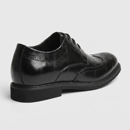 Rear three-quarter view of a single FORCIANO FAIRMONT black height increasing dress shoe showing brogue side detailing and heel profile.