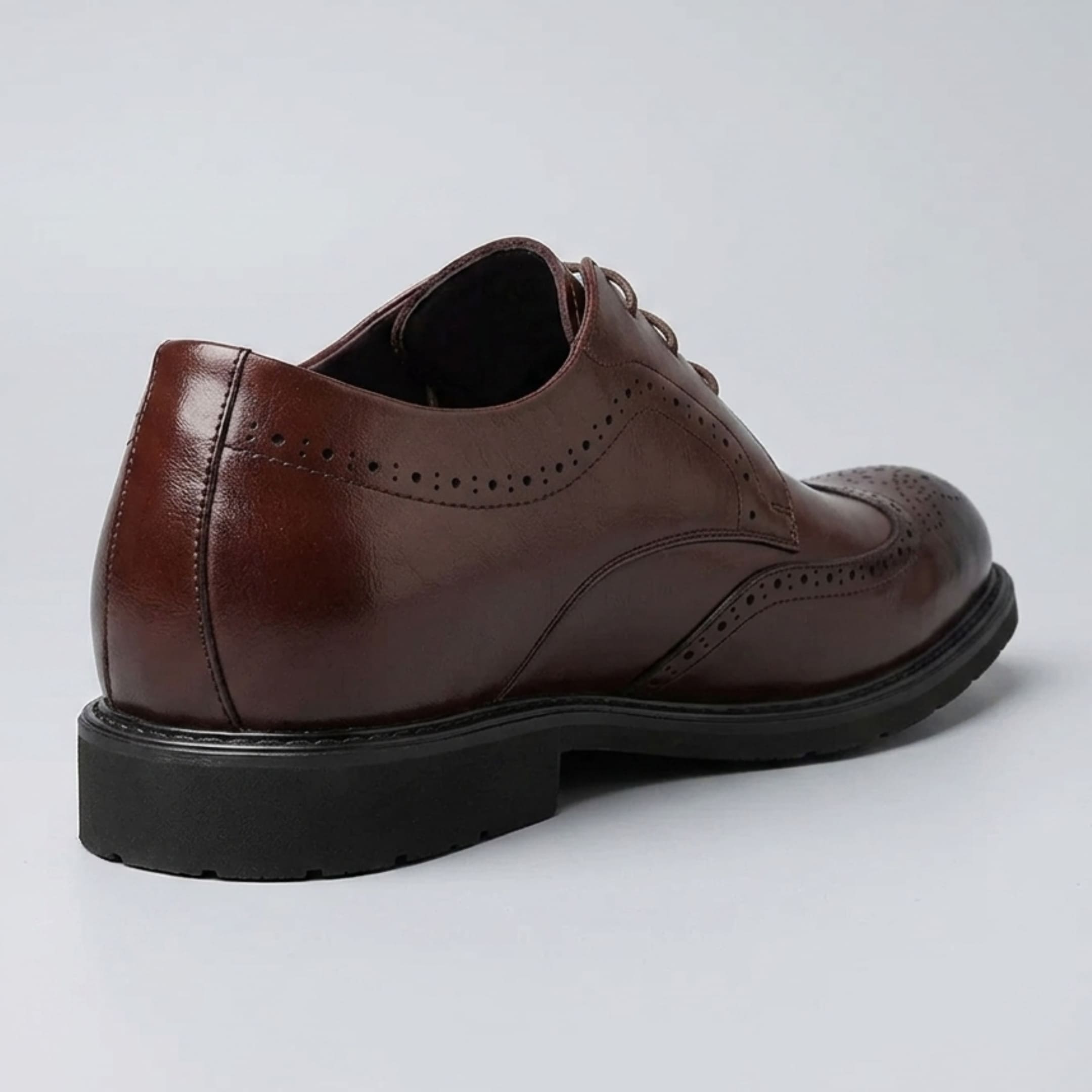 Rear three-quarter view of a FORCIANO FAIRMONT brown height increasing dress shoe showing the heel, side panels and brogue details.
