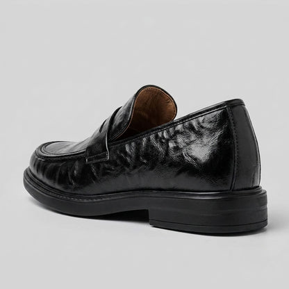 FORCIANO KINGSLEY black leather height increasing loafer shown from a rear three-quarter angle, highlighting the heel and leather finish.