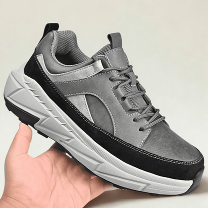 FORCIANO NORTHRIDGE gray and black height increasing sneakers held in hand from a front three-quarter angle with contrasting white sole.