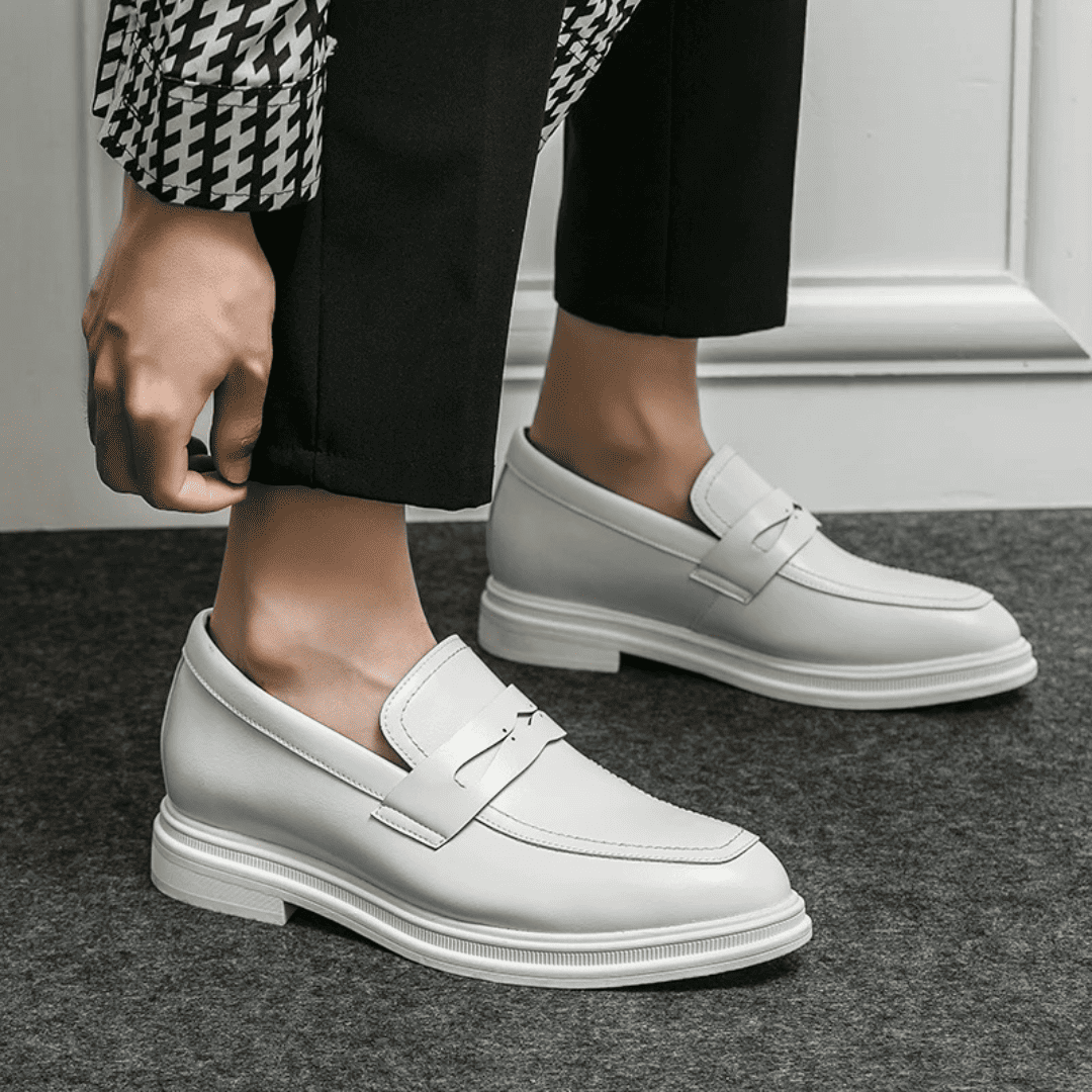 FORCIANO PANTHERA white leather elevator loafers worn with black trousers in a side-angle lifestyle view showing both shoes.