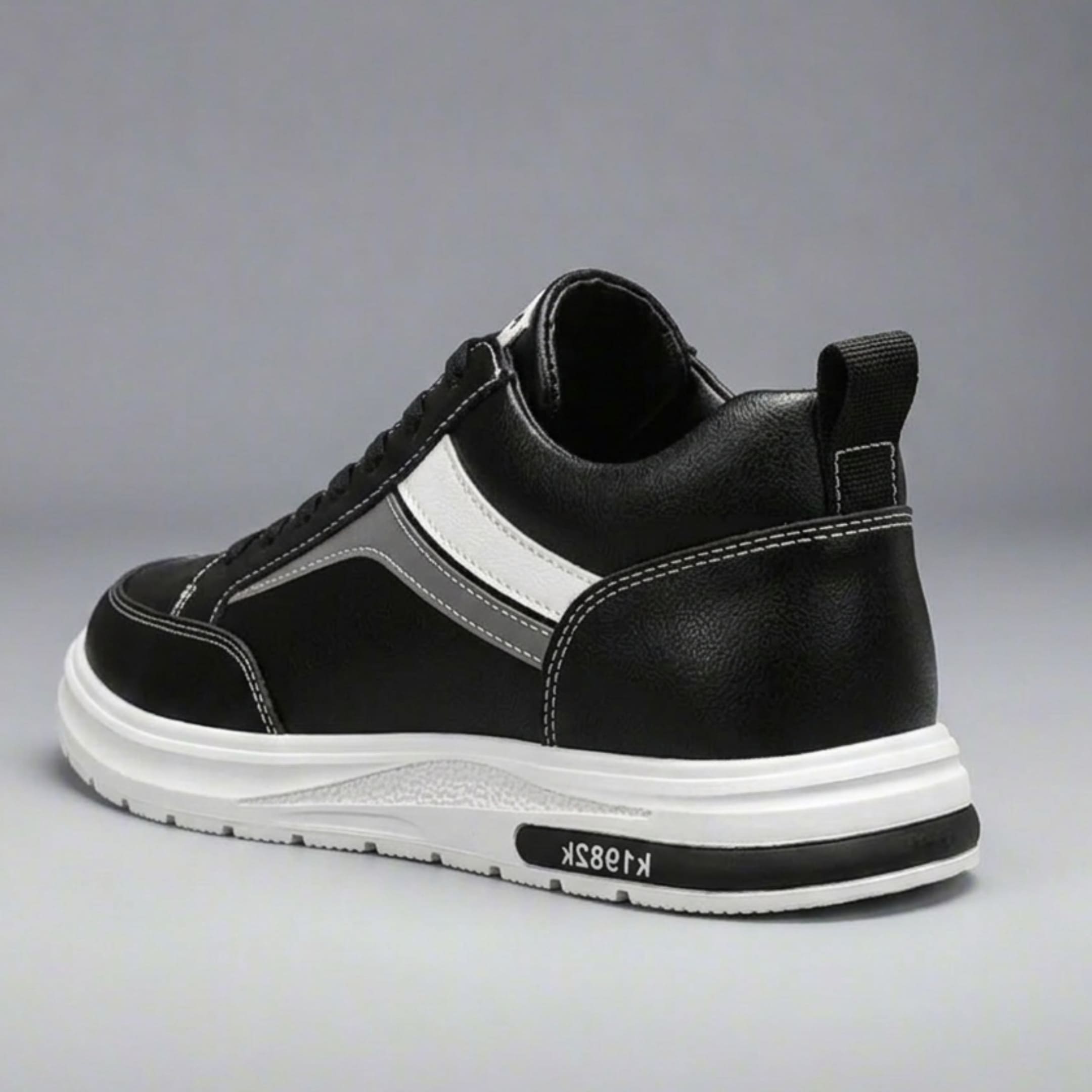 FORCIANO PRIME black height increasing sneakers with white and gray reflective accents shown from a rear three-quarter angle, featuring contrast stitching and a white sole.