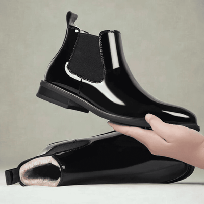 FORCIANO SILVAN black Chelsea Height Increasing Boots shown as a pair, with one boot held above the other and wool-cushioned lining visible inside the lower boot.